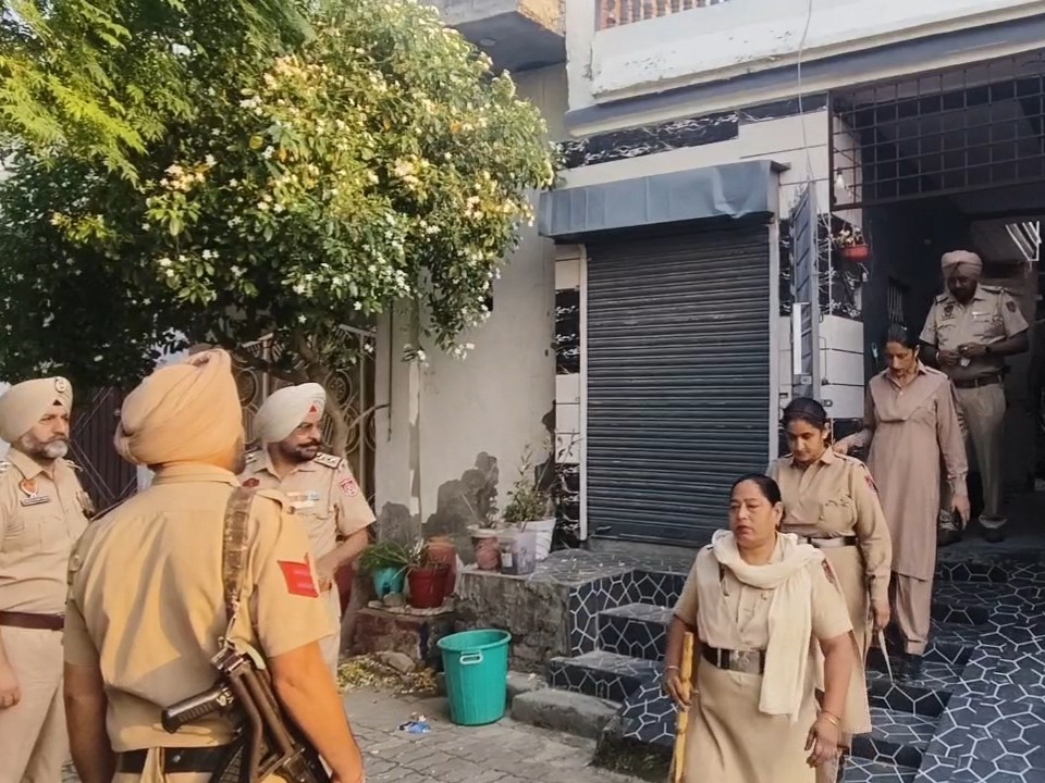 छापेमारी के बाद घर से बाहर आते पुलिसकर्मी।