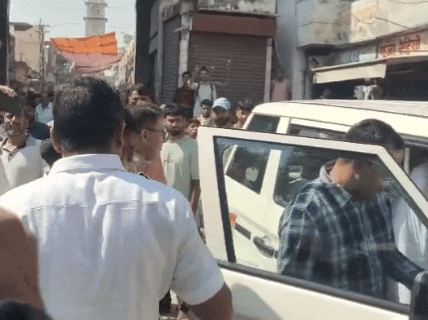 युवक को गाड़ी में डालकर ले जाते हुए।