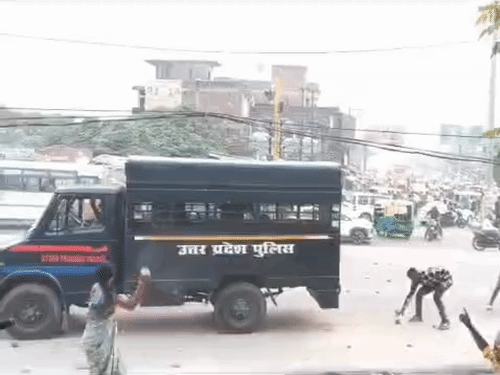 पुलिस वैन पर पथराव करते लाेग, अंदर छिपे पुलिसकर्मी बचाव करते हुए