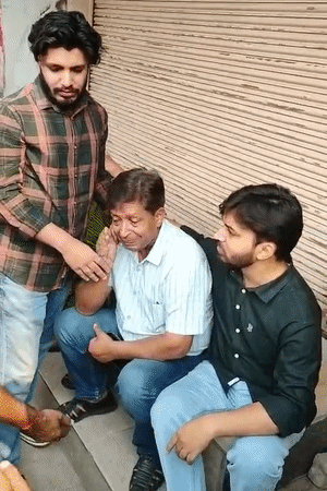 दुकान मालिक बाहर बैठकर रो रहे हैं। लोग उन्हें समझा रहे हैं।