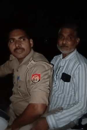 पुलिस के साथ बैठे एक शख्स पर वहां मौजूद लोग पीड़ितों को भ्रमित करने का आरोप लगा रहे हैं।