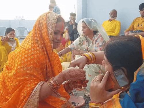 व्रती नारंगी सिंदूर लगाती हुई, जो सूर्य देव का प्रतीक माना जाता है।