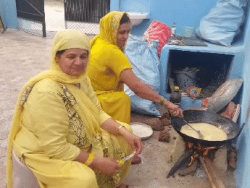 अमित पंघाल के घर चूल्हे पर हलवा बनाते हुए परिवार की महिलाएं।
