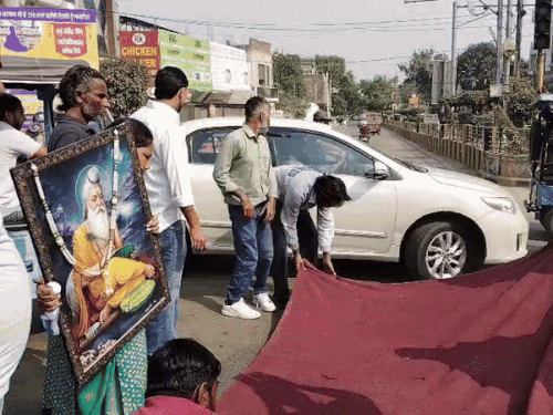 वाल्मीकि महाराज की फोटो लेकर चौक में धरना लगाने पहुंचे प्रदर्शनकारी।