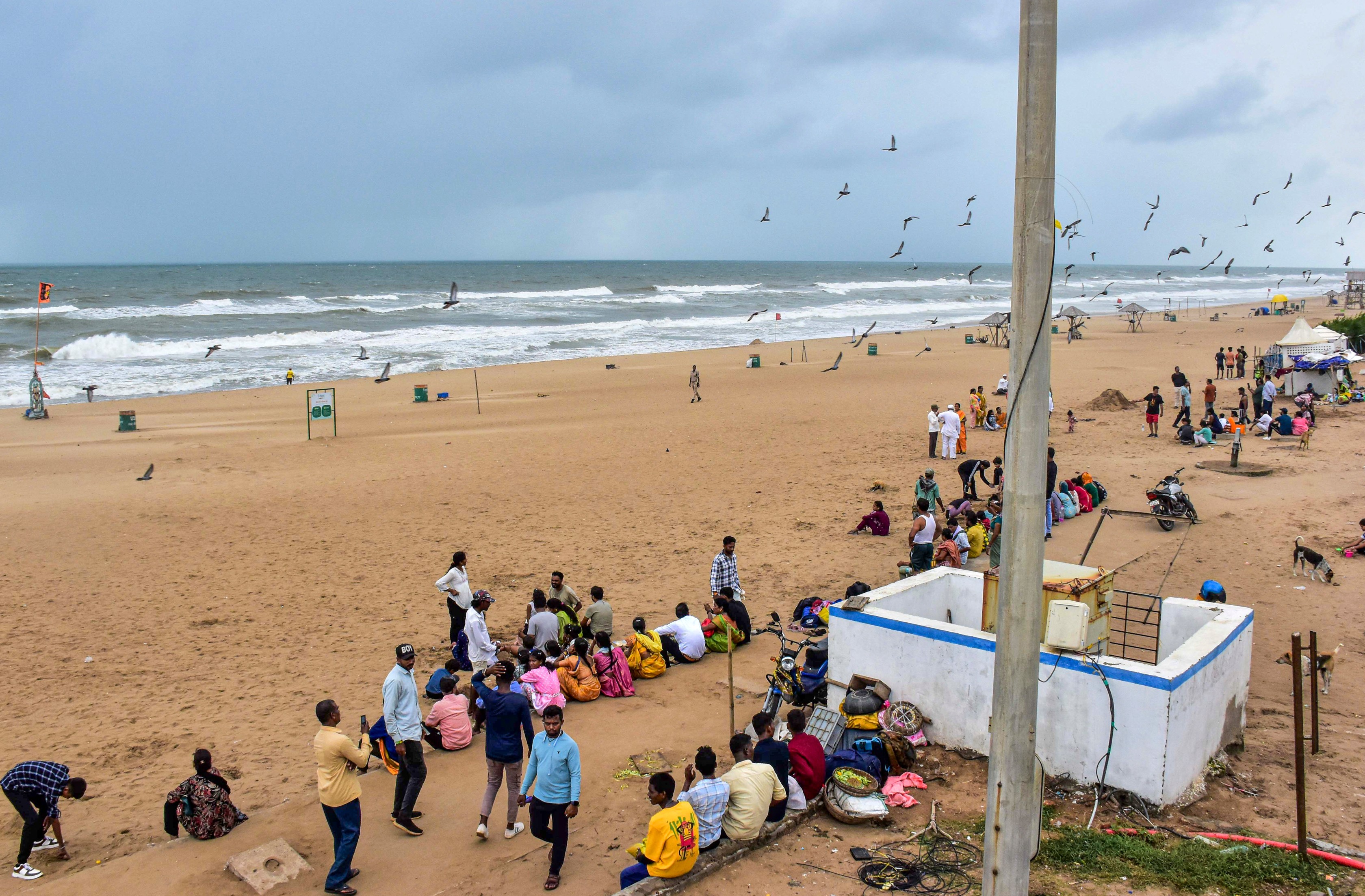 पुरी में समुद्र किनारे बैठे लोग। यहां मोन्था चक्रवात के कारण मंगलवार रात को समुद्र में 4 से 7 फीट ऊंची लहरें उठीं।