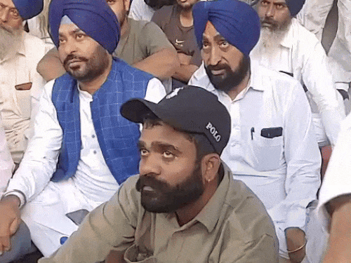 धरने में बैठा बुजुर्ग का बेटा।