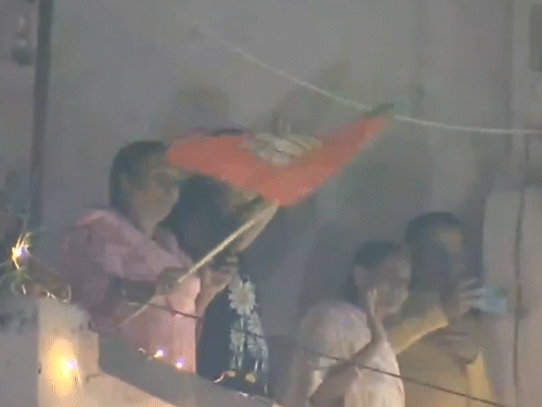 घर की बालकनी से भाजपा का झंडा दिखाती महिला।