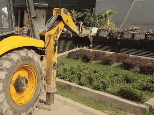 मॉल के बाहर निर्माण को तोड़ते हुए जेसीबी।