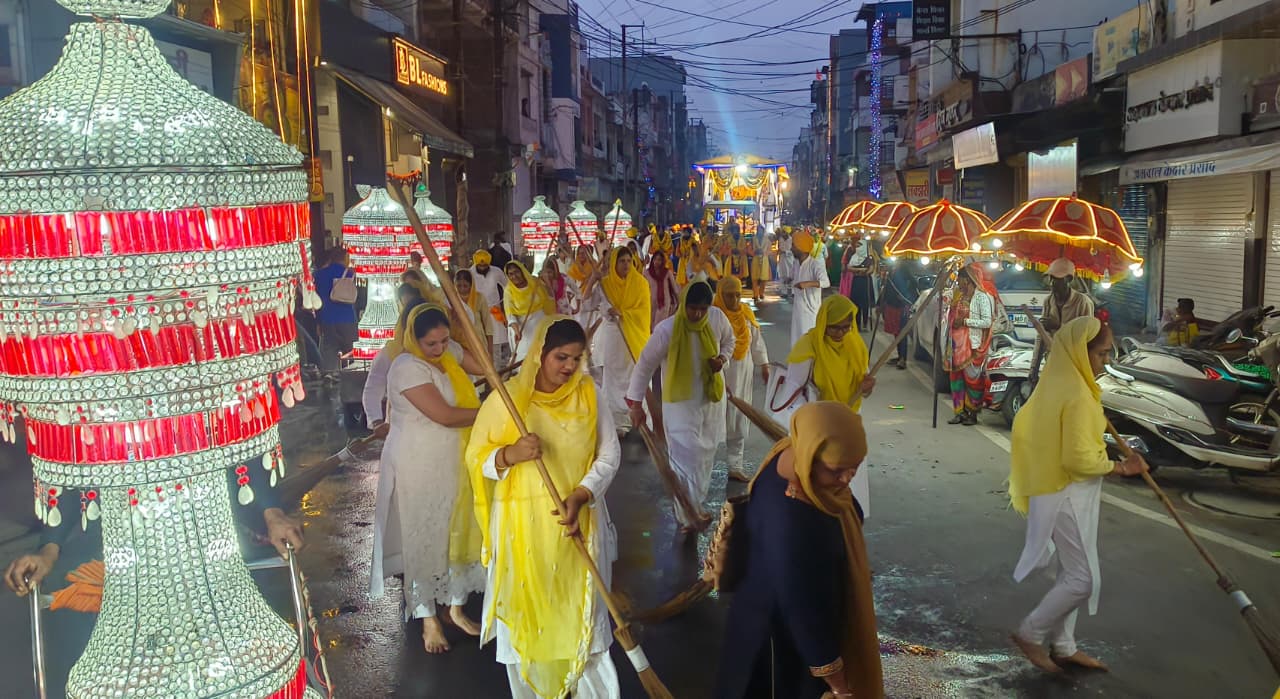 गुरु ग्रंथ साहिब के आगे समाज की महिलाएं सड़क की सफाई करते हुए।