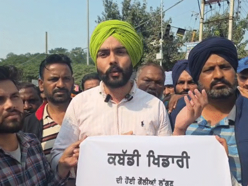 प्रदर्शन में पोस्टर दिखाकर नारेबाजी करता युवक।