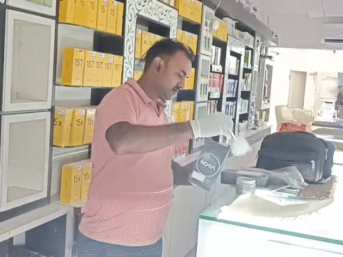शॉप के अंदर मोबाइल डिब्बों की जांच करती हुई पुलिस की टीम।