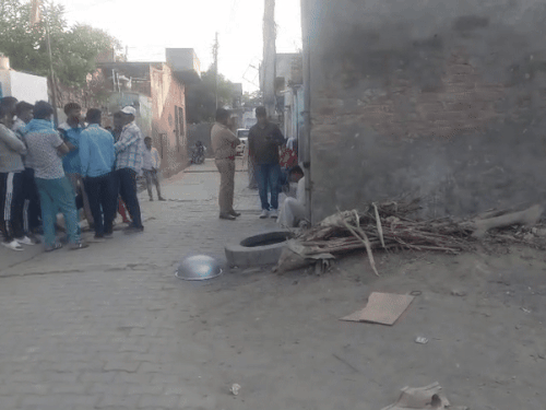 मृतक धर्मवीर के घर के बाहर खड़े पुलिस के अधिकारी और ग्रामीण।