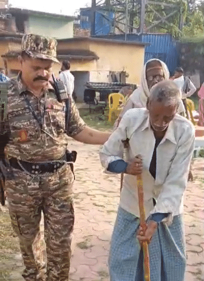 मतदान करने आए बुजुर्ग की मदद करते सुरक्षा कर्मी।