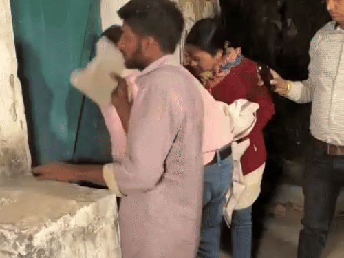 ईंट मरकर दरवाजा खोलने की कोशिश करते लोग।