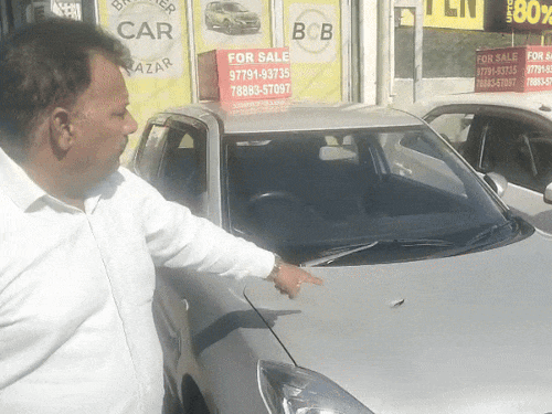 कारों में लगी गोली दिखाता कार मालिक। गोलीबारी में दो कारों को नुकसान पहुंचा है।