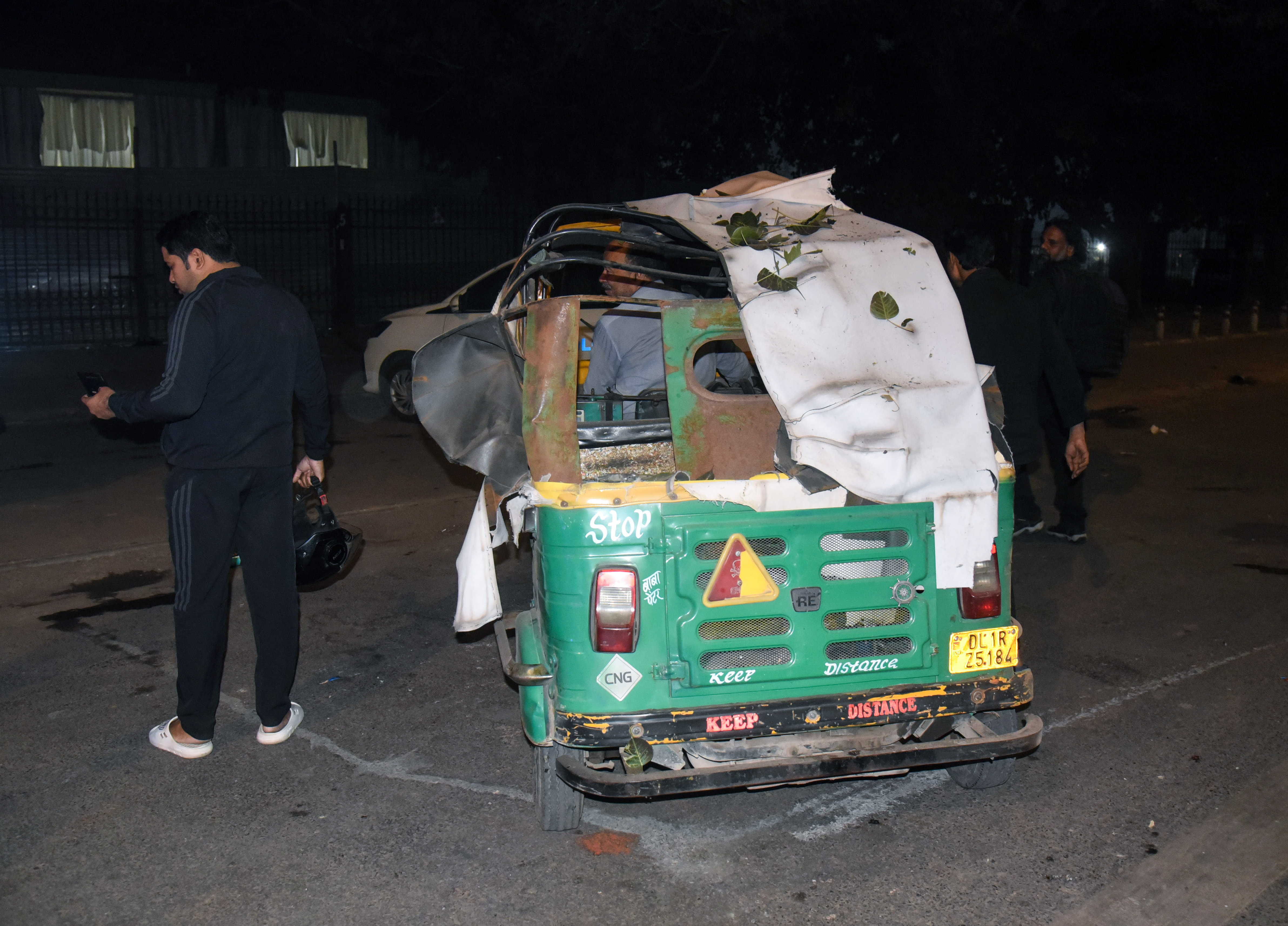 ब्लास्ट में क्षतिग्रस्त ऑटो ले जाता शख्स।