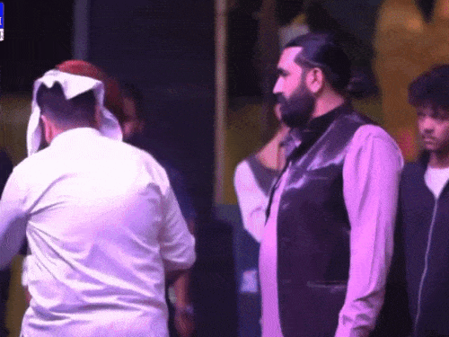 सिंगर को स्टेज पर कड़ा देता व्यक्ति।