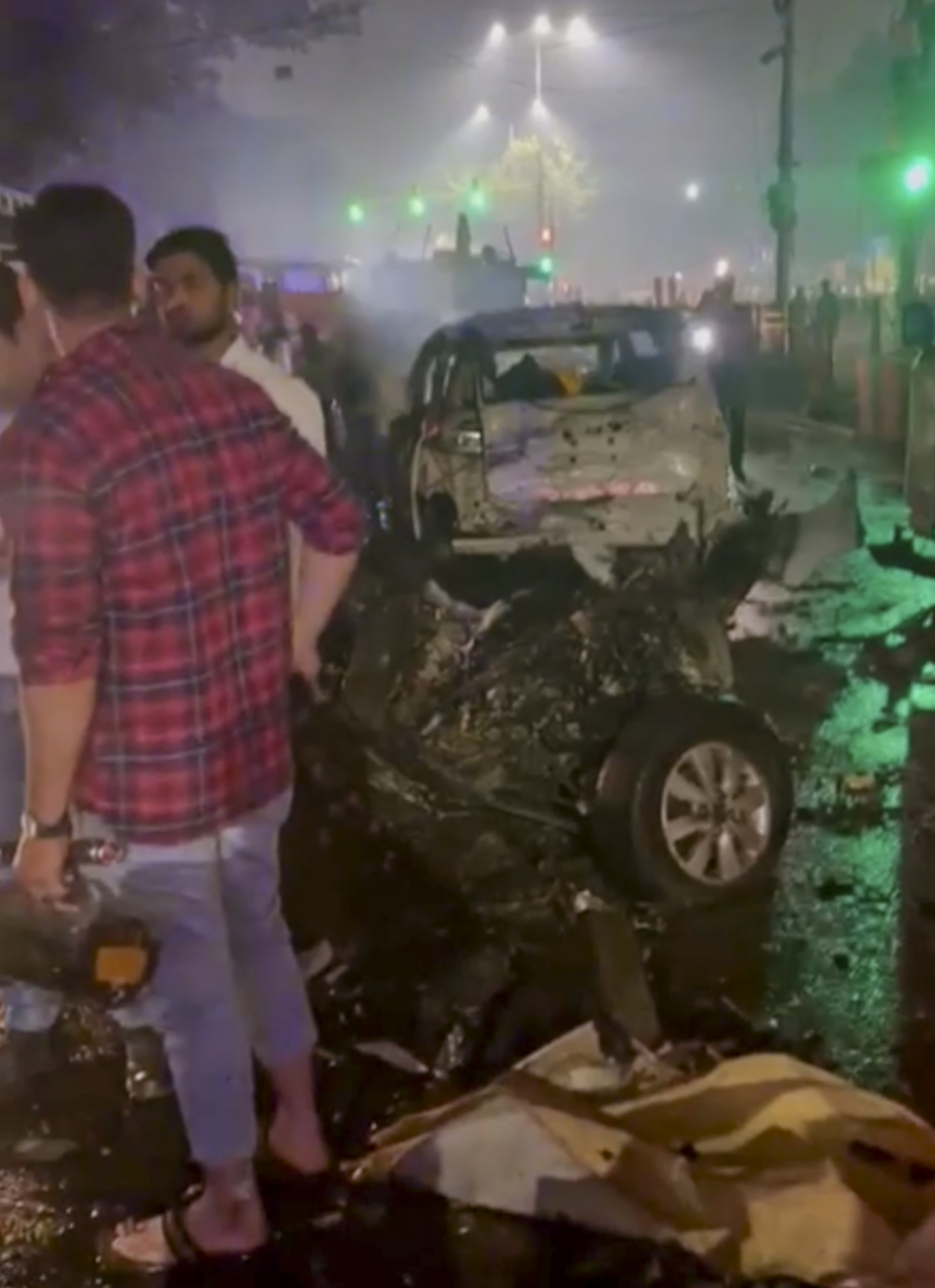 पार्किंग में मौजूद एक कार का अगला हिस्सा पूरी तरह से डैमेज हो गया। बॉडी ब्लास्ट में उड़ गई। मौके पर मौजूद लोग गाड़ियों की हालत देखते हुए।