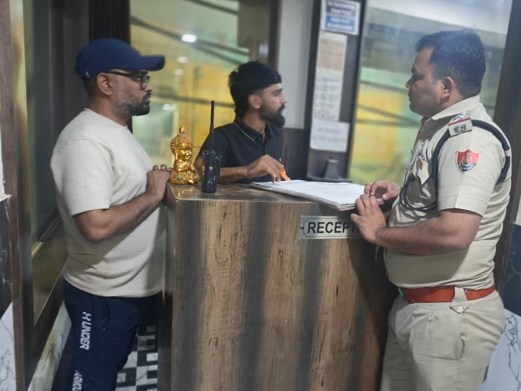 होटल में गेस्ट रजिस्ट्रर की जांच करते पुलिस अधिकारी।