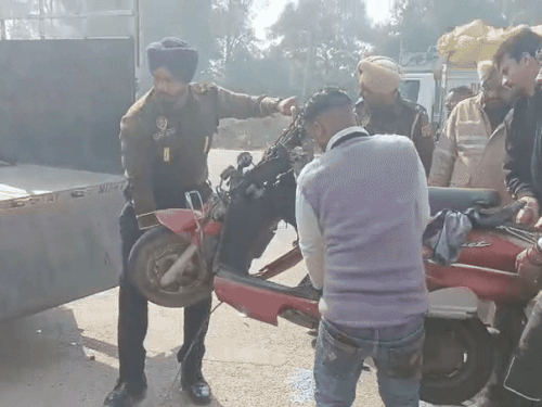 एक्सीडेंट हुई बाइक को रोड से हटाते हुए पुलिस कर्मचारी।