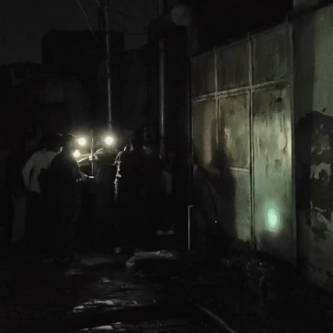 आग लगने पर शोरूम का पिछला गेट खोलने का प्रयास करते हुए लोग।