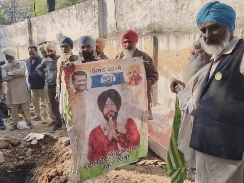 AAP नेता का पोस्टर लेकर विरोध करते किसान।