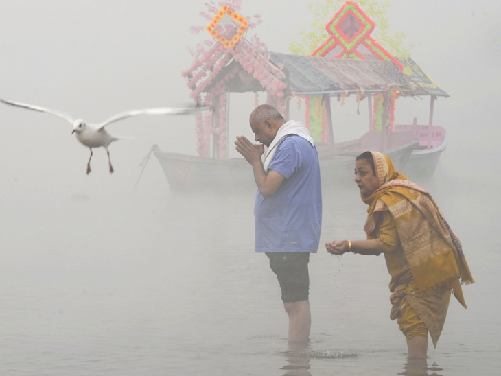 मध्य प्रदेश: जबलपुर में नर्मदा नदी में लोग पूजा करते लोग। सर्दी के चलते नदी पर कोहरा छा गया।