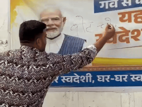 पानीपत शहर में पुराना बस स्टैंड के पास दीवार पर लगे PM के पोस्टर पर वोट चोर गद्दी छोड़ का नारा लिखता युवक।