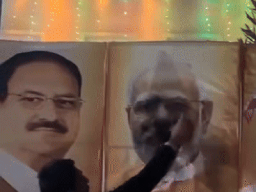 पोस्टर पर लगी पीएम नरेंद्र मोदी की फोटो पर कालिख पोतते हुए युवा।