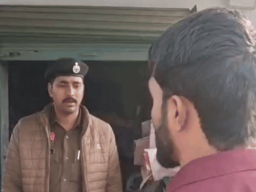 बाजार में दुकानदारों से पूछताछ करते हुए पुलिस के कर्मचारी।