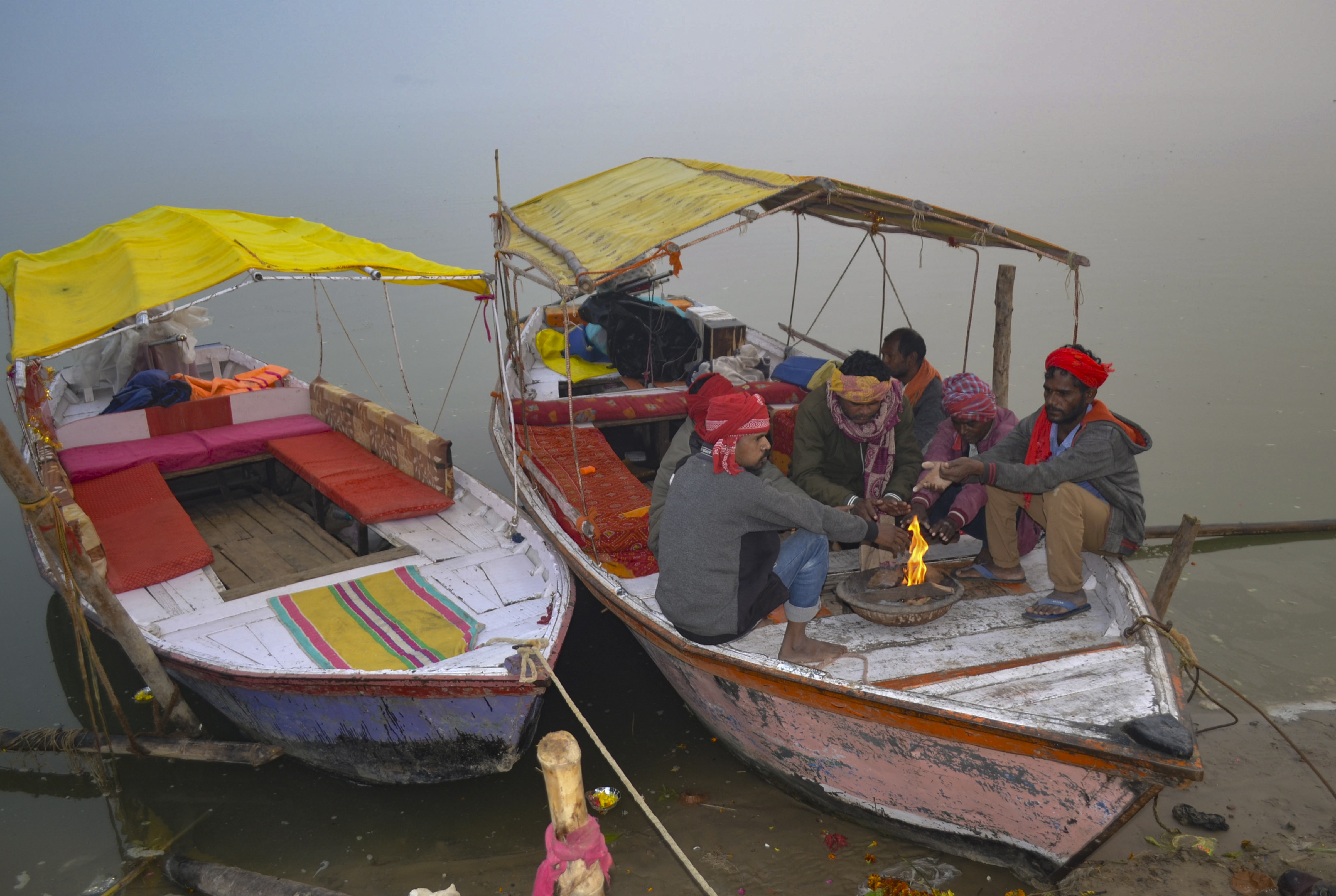 उत्तर प्रदेश के मिर्जापुर में शनिवार सुबह गंगा नदी के किनारे धुंध भरी सर्दियों में लोगों ने नाव पर ही अलाव जला लिया।