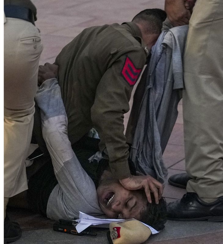दिल्ली में इंडिया गेट के पास एक प्रदर्शनकारी को हिरासत में लेते पुलिसकर्मी।