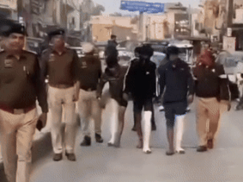 बाजार में आरोपियों को घुमाते हुए पुलिस।