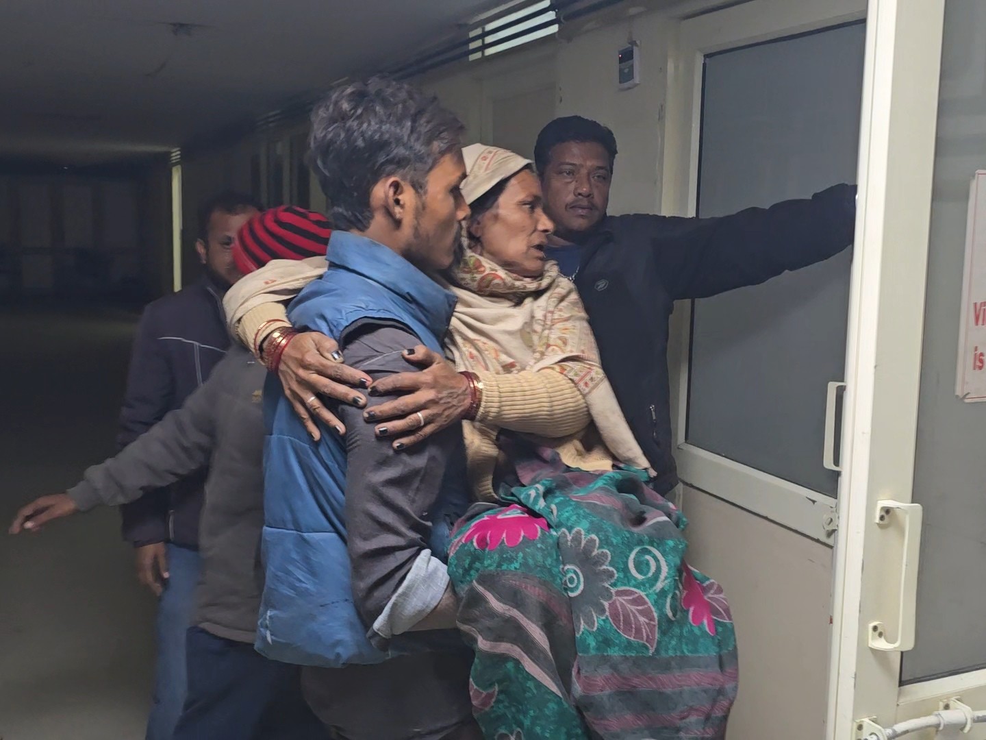 घायल महिला को गोद में उठाकर ले जाता युवक।
