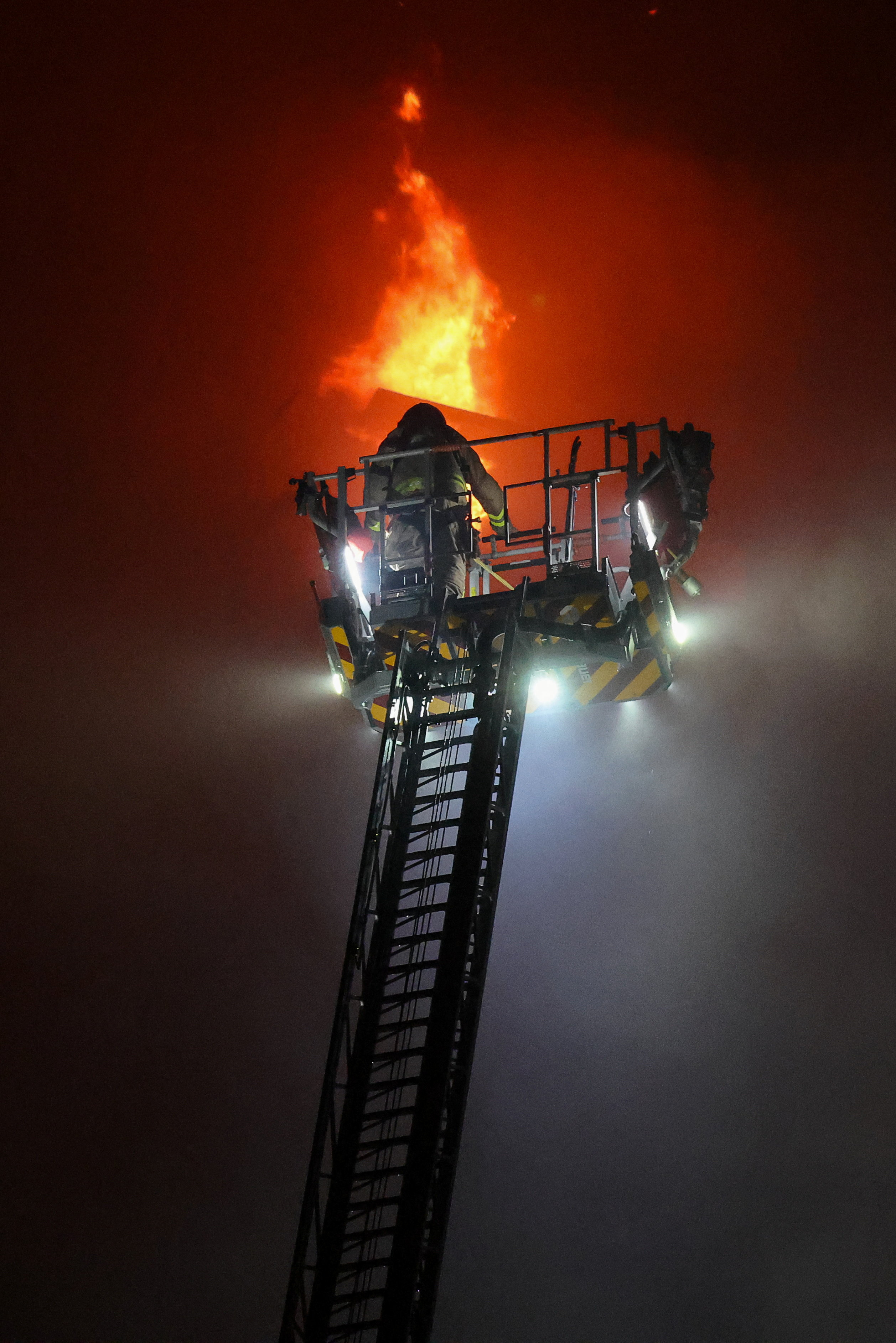 रेस्क्यू वर्कर आग बुझाने की कोशिश करते हुए। अभी तक आग पर पूरी तरह काबू नहीं पाया गया है।