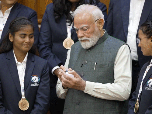 क्रिकेट बॉल पर साइन करते हुए PM मोदी।