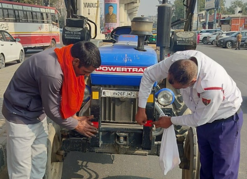 दिल्ली-रोहतक रोड पर ट्रैक्टर पर रिफ्लेक्टर टेप लगाते पुलिसकर्मी।