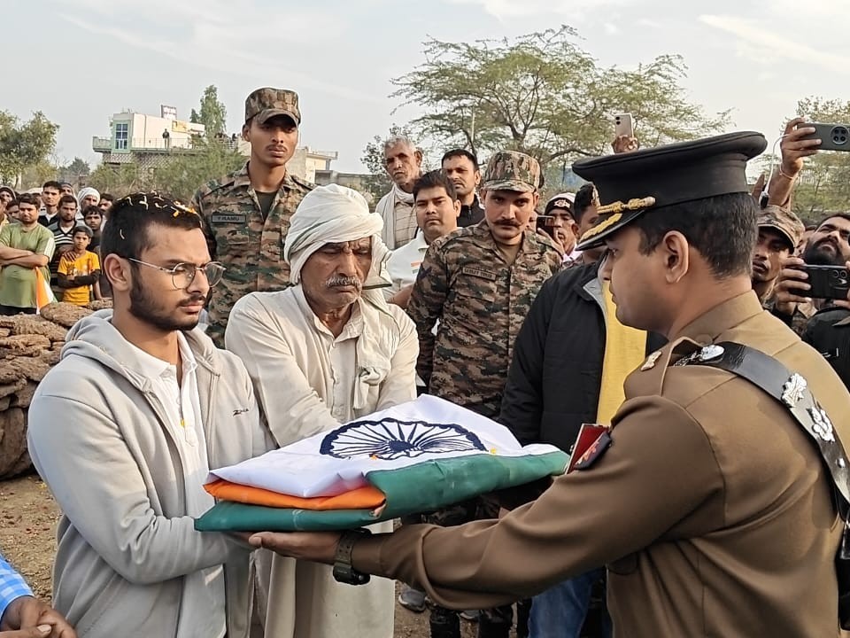 शहीद के परिजनों को तिरंगा सौंपते हुए।