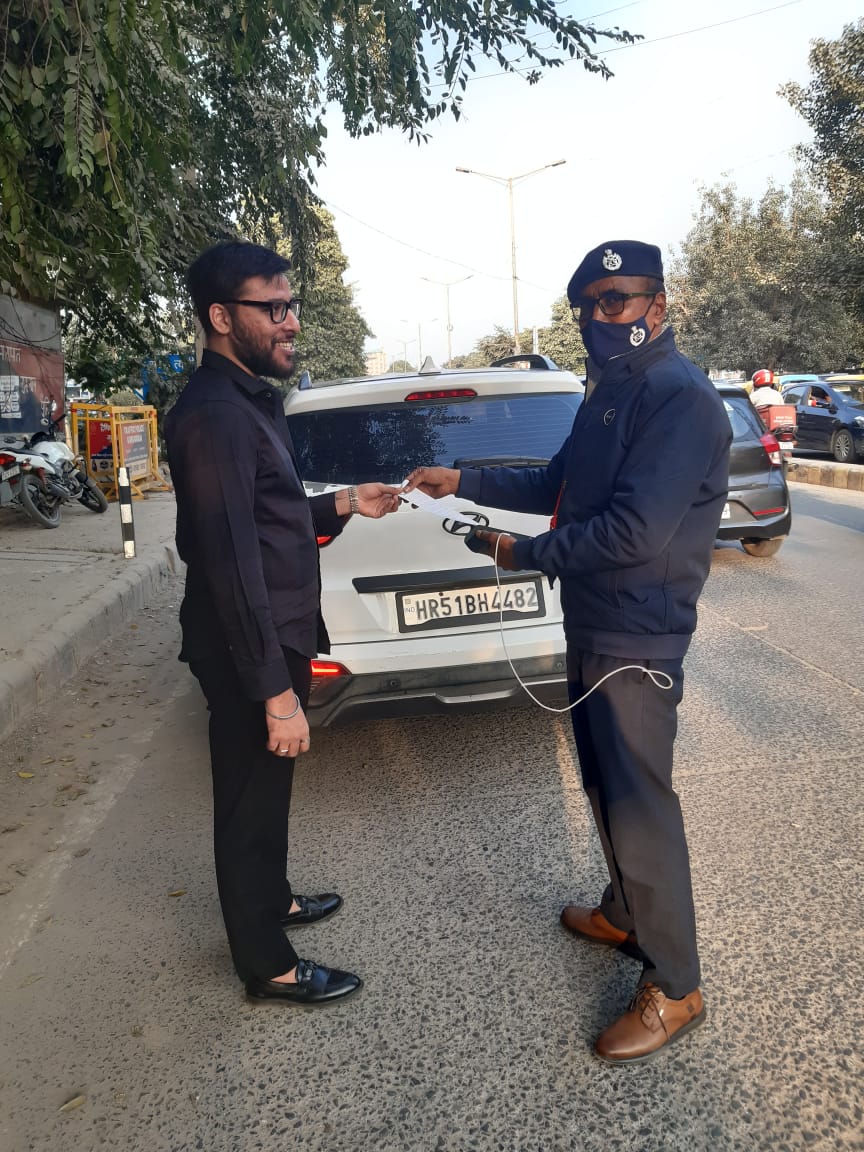 गुरुग्राम में ब्लैक फिल्म लगी कार का चालान काटता ट्रैफिक पुलिसकर्मी।