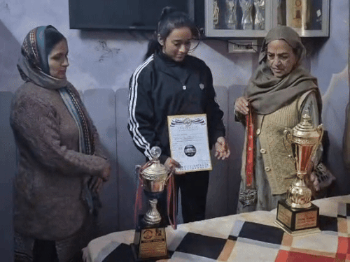 दादी कोमलप्रीत के गले में मेडल डालते हुए साथ में है उसकी मां।