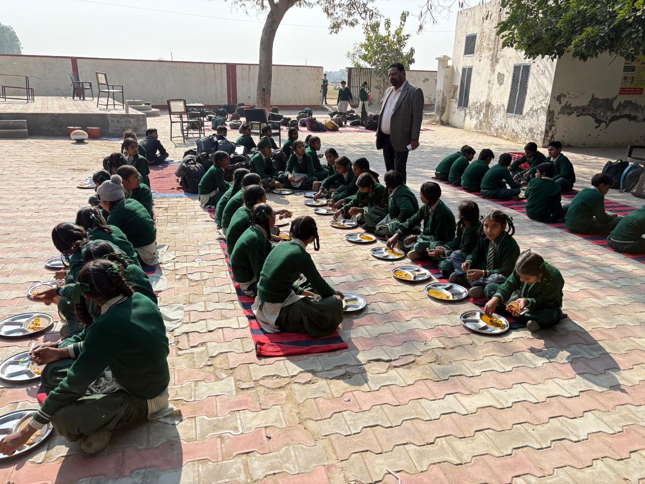 जमीन पैर बैठकर खाना खा रहे बच्चे