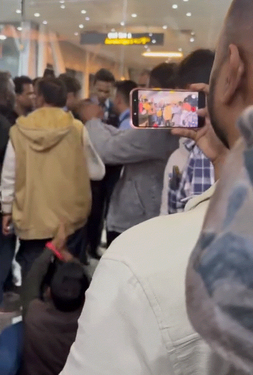 यात्री एयरपोर्ट में फ्लोर पर बैठकर ताली बजाते हुए प्रदर्शन करते रहे।