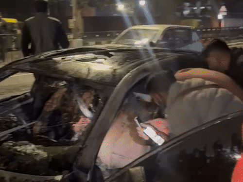 जलने के बाद कार को देखते लोग।