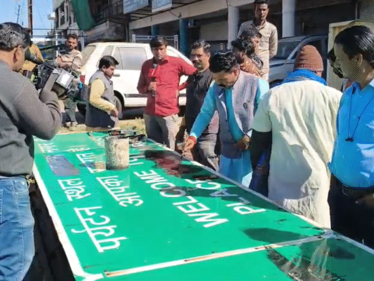 बोर्ड पर इस्लाम नगर लिखे नाम को हटाते लोग।