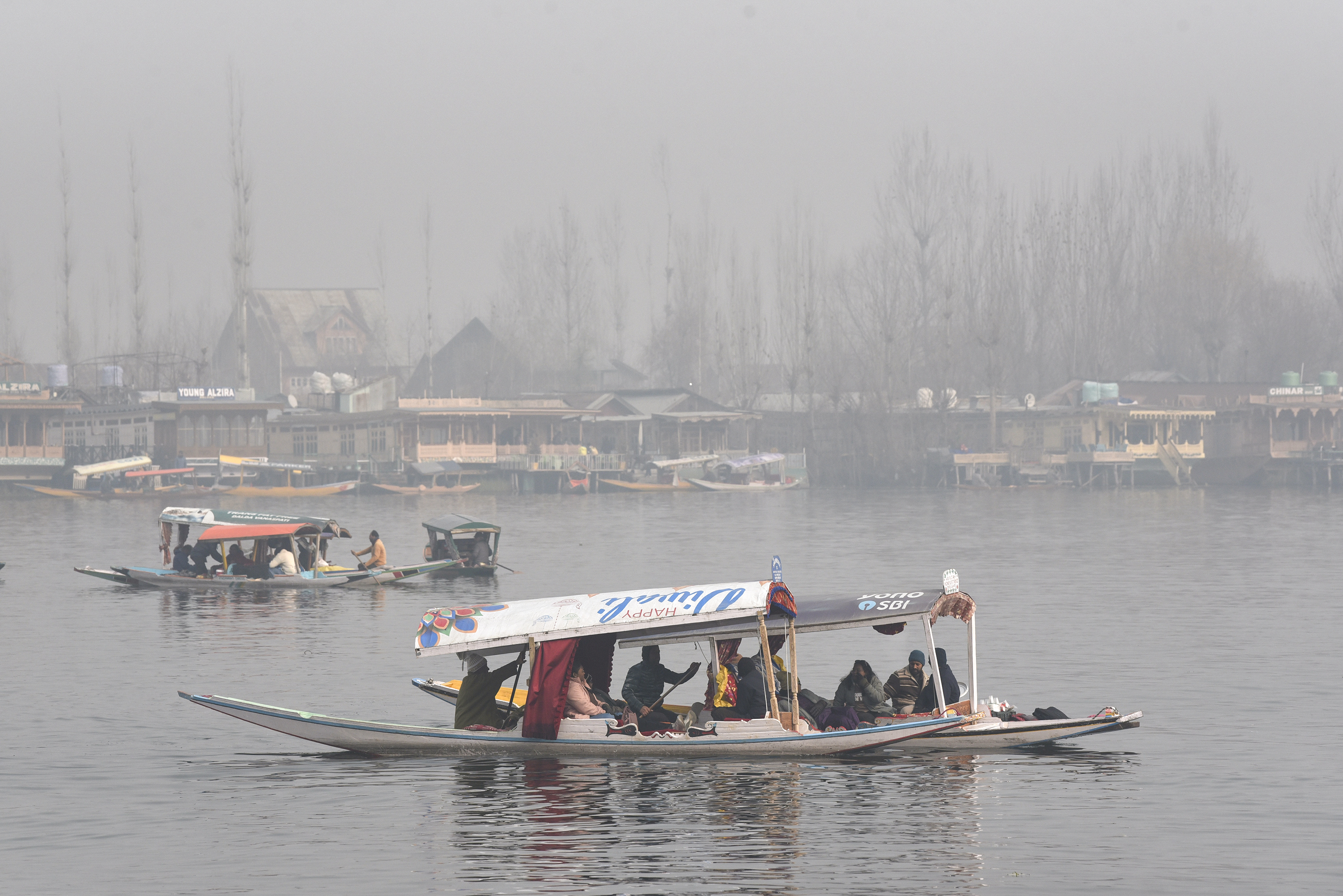 श्रीनगर में डल झील पर गुरुवार को सर्दी के बीच पर्यटक शिकारा की सवारी करने पहुंचे।