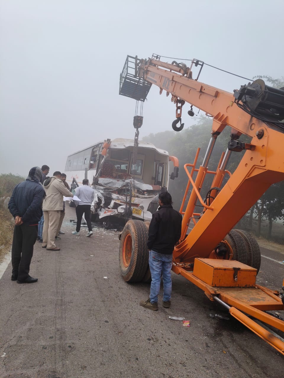 हादसे में क्षतिग्रस्त हुई बस को सड़क से हटाती जेसीबी।