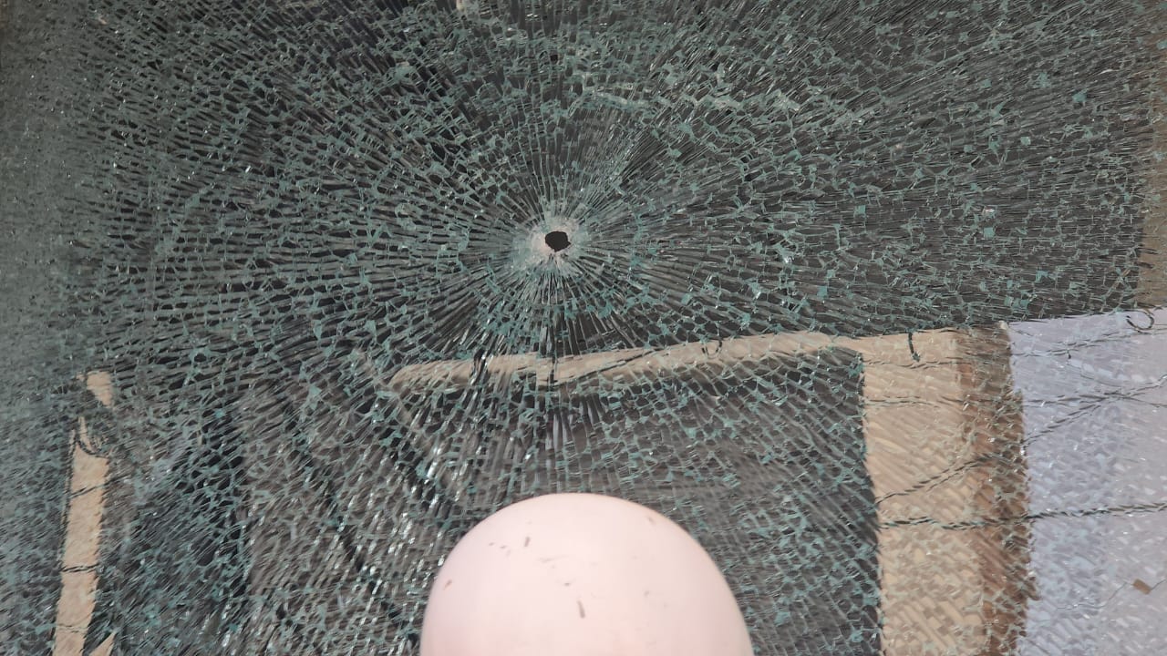 दुकान के शीशे पर गोली लगने का निशान।