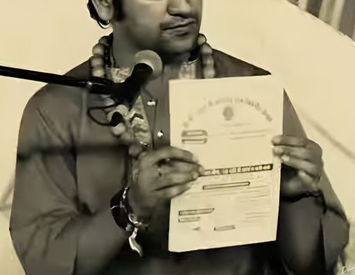 ढांडा न्योलीवाला की एल्बम में धीरेंद्र कृष्ण शास्त्री को पर्चा दिखाते हुए फिल्माया गया है।