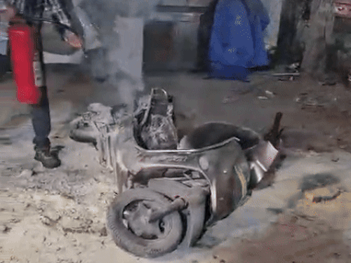 एक्टिवा में लगी आग पर काबू पाता कर्मचारी।