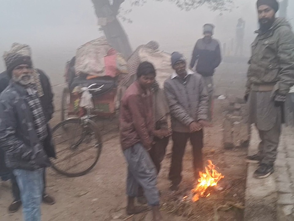 कोहरे और सर्दी बढ़ने के कारण सड़क पर आग जलाकर सेकते लोग।